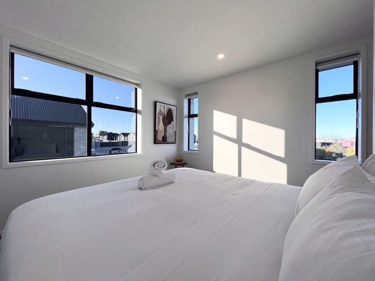 A bedroom with a large bed, multiple windows, and a view of the outside.