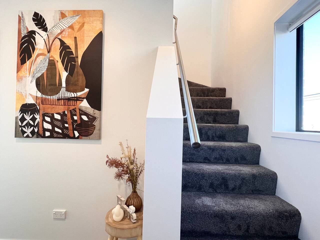 A staircase with a metal handrail and a window to the right.