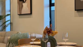 A dining table set with plates, wine glasses, and cutlery, with a vase of flowers and a decorative bowl in the center.
