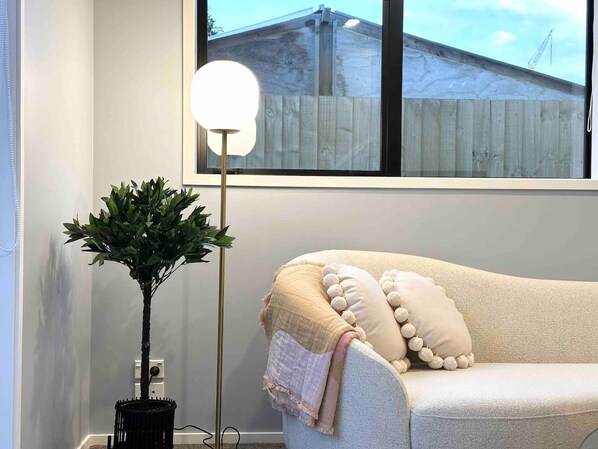 A room with a white sofa, a floor lamp, and a potted plant.