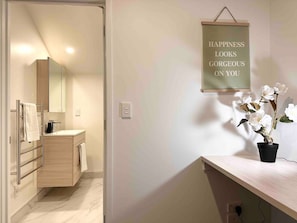 Un baño moderno con tocador, espejo y un cartel en la pared.