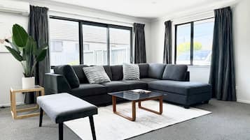 A modern living room with a sectional sofa, a coffee table, and a small side table.