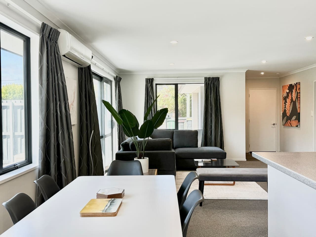 Ein modernes Wohnzimmer mit einer Couch, einem Esstisch und einer Küchenzeile.