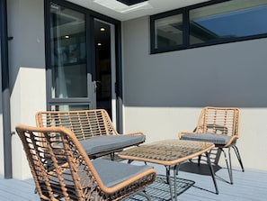 A balcony with wicker furniture and a glass door.