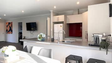 A modern kitchen with a built-in island, stainless steel appliances, and a flat-screen TV mounted on the wall.