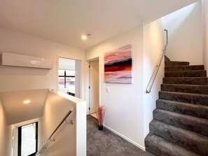 A staircase with a handrail, carpeted steps, and a wall-mounted painting.