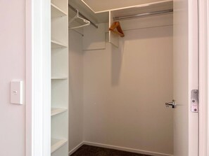 A walk-in closet with open shelves, a hanging rod, and a door with a lock.