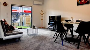 Un salon moderne comprenant un canapé, une table basse et un coin repas avec des chaises et un téléviseur.