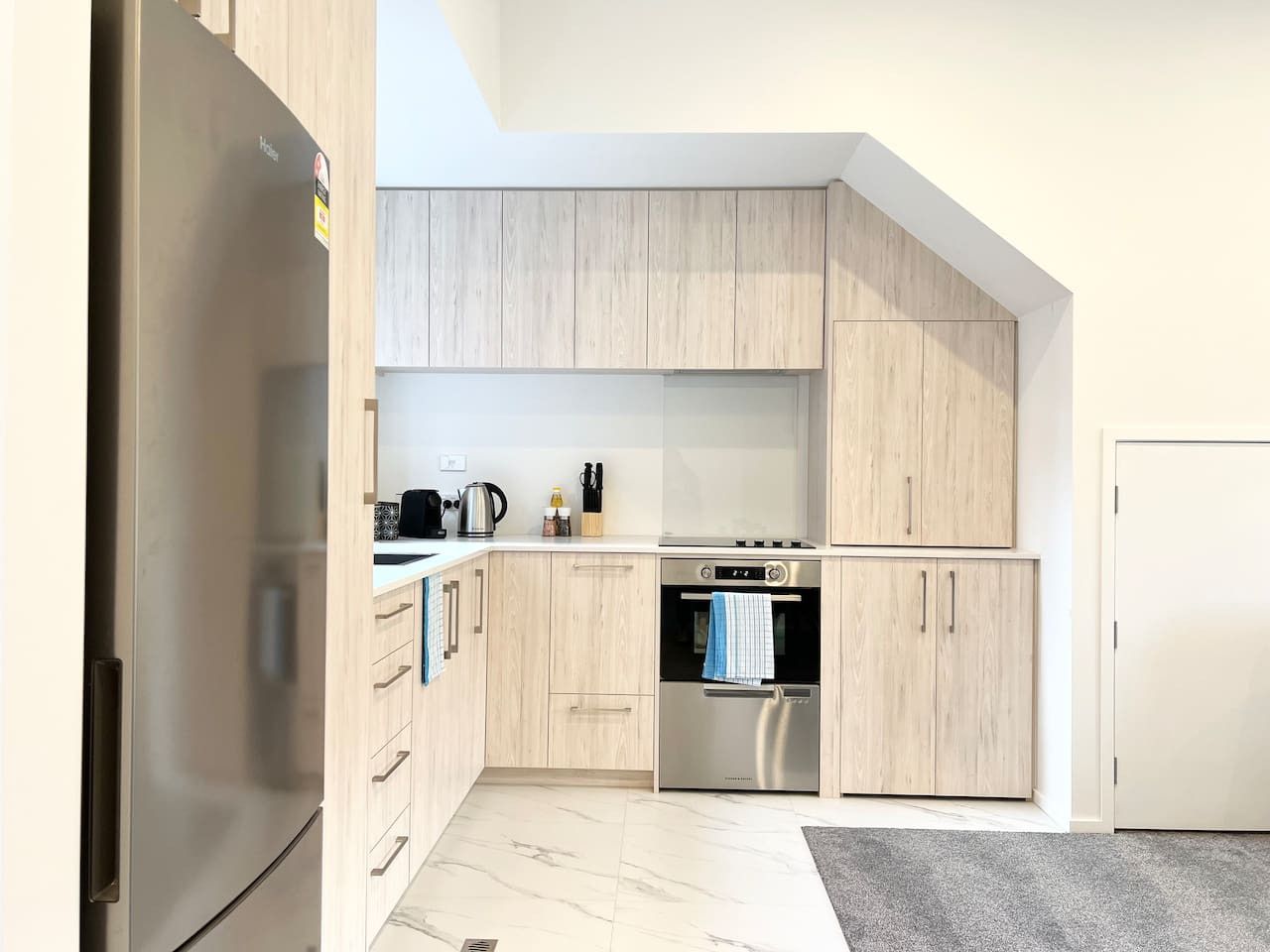 Eine moderne Küche mit hellen Holzschränken, Edelstahlgeräten und einem eingebauten Backofen.