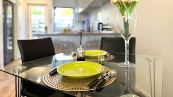 A dining table set with green plates, cutlery, and a vase with flowers.