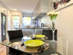 A dining table set with green plates, cutlery, and a vase with flowers. - Peacock townhouse with garage and balcony in Christchurch (Christchurch)