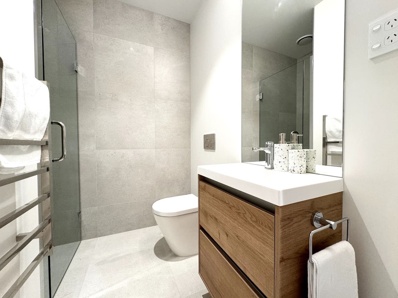 A modern bathroom with a shower, toilet, and vanity.