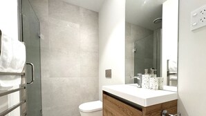 A modern bathroom with a shower, toilet, and vanity.