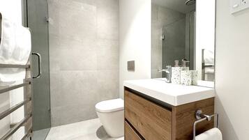 A modern bathroom with a shower, toilet, and vanity.