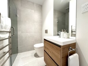 Un baño moderno con ducha, inodoro y tocador.