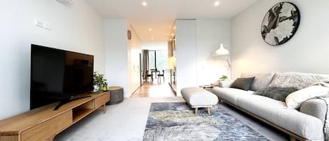 Una sala de estar moderna con un televisor de pantalla plana, un sofá, una mesa de centro y un tapete estampado.