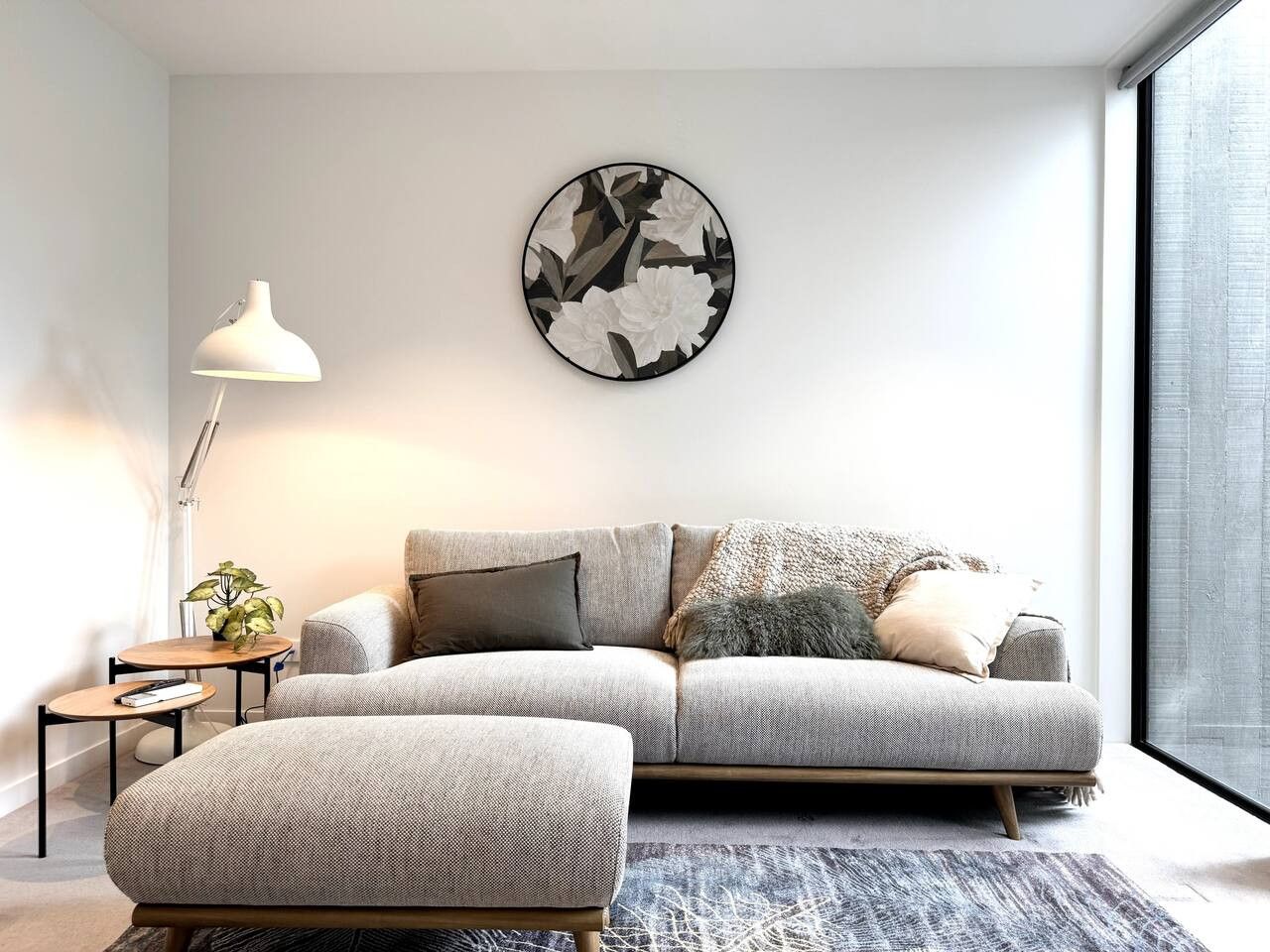 A modern living room with a grey sofa, a round coffee table, and a side table with a lamp.