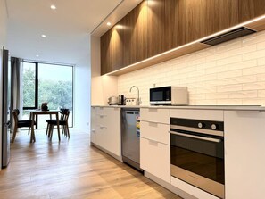 Una cocina moderna con armarios blancos, un microondas integrado y un lavavajillas.