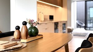 A modern kitchen with wooden cabinets, a dining area with a wooden table, and a view of the living room.