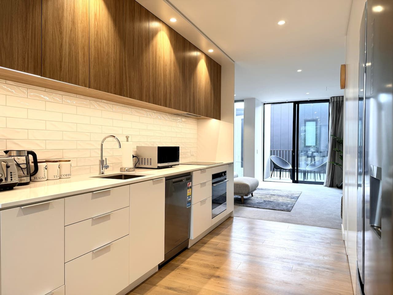 A modern kitchen with white cabinetry, a built-in microwave, and a dishwasher.