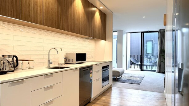 A modern kitchen with white cabinetry, a built-in microwave, and a dishwasher.