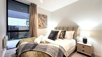 A bedroom with a bed, a nightstand, a lamp, and a window with curtains.