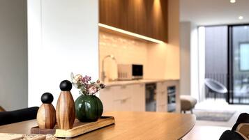 A modern kitchen with wooden cabinets, a dining area with a wooden table, and a view of the living room.