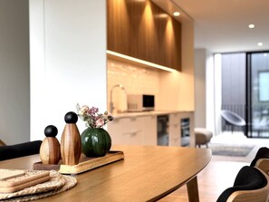 Eine moderne Küche mit Holzschränken, ein Essbereich mit Holztisch und Blick zum Wohnzimmer.