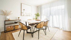A dining area with a round table, six chairs, a white rug, a plant, and a mirror on the wall. - Cashel penthouse with city balcony and parking in Christchurch (Christchurch)