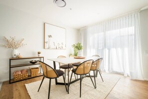 A dining area with a round table, six chairs, a white rug, a plant, and a mirror on the wall. - Luxury Penthouse in City Private central live (Christchurch)
