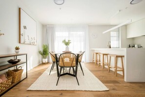 A modern kitchen with white cabinets, wooden countertops, and a central island with stools. - Cashel penthouse with city balcony and parking in Christchurch (Christchurch)