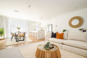 A modern living room with a sofa, coffee table, and dining area.