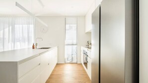 A modern kitchen with white cabinetry, a wooden floor, and a stainless steel refrigerator. - Cashel penthouse with city balcony and parking in Christchurch (Christchurch)