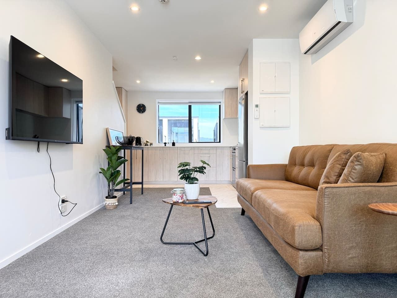 A modern living room with a sofa, a coffee table, and a TV mounted on the wall.