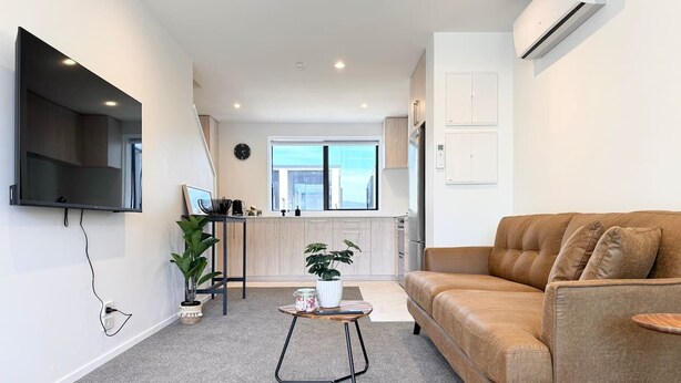 Una sala de estar moderna con un sofá, una mesa de centro y un televisor montado en la pared.