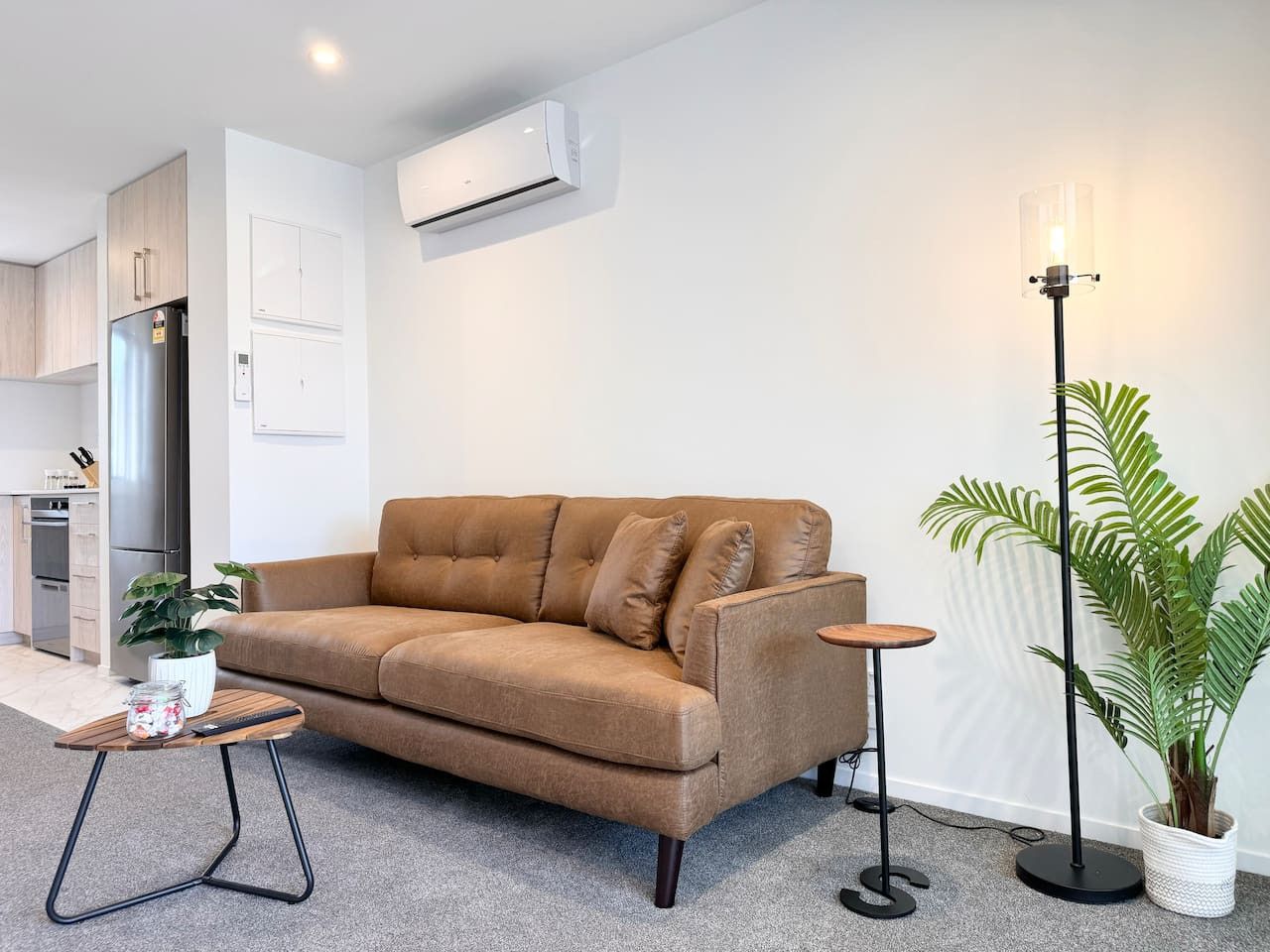Una sala de estar moderna con un sofá, una mesita con una planta y una lámpara de pie.