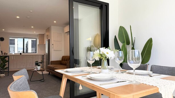 Comedor con una mesa de madera dispuesta para cuatro personas, rodeado de sillas tapizadas en gris.