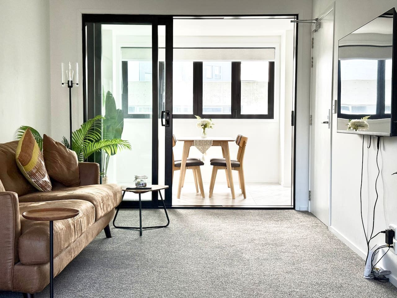 Una sala de estar moderna con un sofá, una mesita y una zona de comedor con sillas.