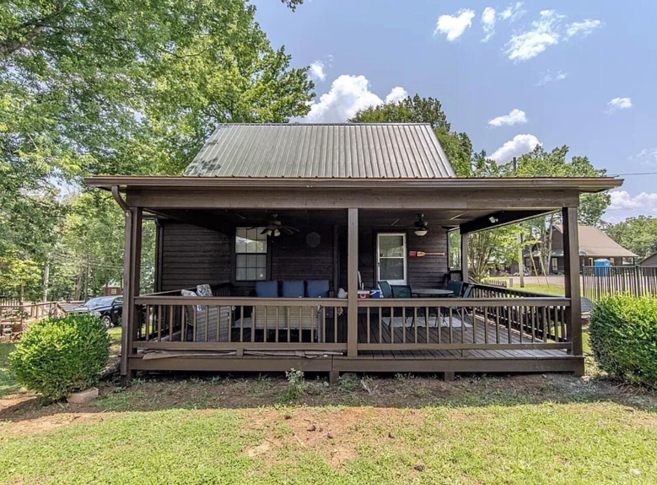 Een houten chalet met een veranda, een overdekt terras en een schouw van baksteen.