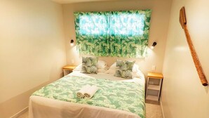 Una camera da letto con un letto, una ventola a soffitto, un comodino e un pannello montato a parete.