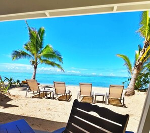 A beach view with palm trees, a sandy beach, and lounge chairs. - Natura Lagoon Bungalow 3 (Rarotonga)