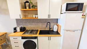 Una cucina compatta con piano cottura a gas, lavello, forno a microonde e lavatrice integrata.