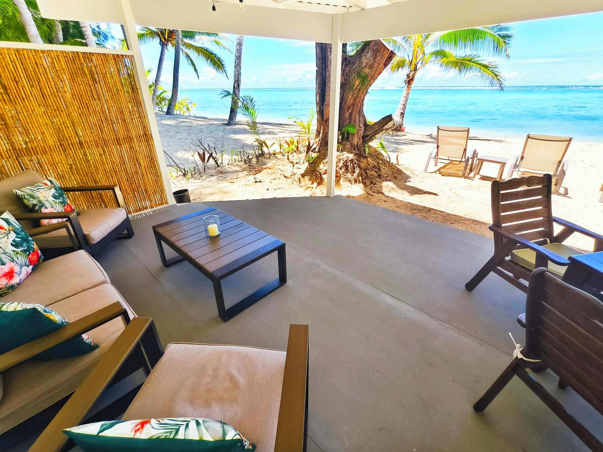 A covered outdoor seating area with a view of the beach and ocean.