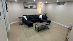 A modern living room with a sectional sofa, a coffee table, and recessed ceiling lighting. - 2 bedroom 1 bathroom basement apartment (Brampton)
