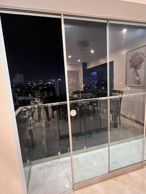 Un interior moderno con un separador de vidrio, vistas nocturnas de la ciudad y un comedor con mesas y sillas.