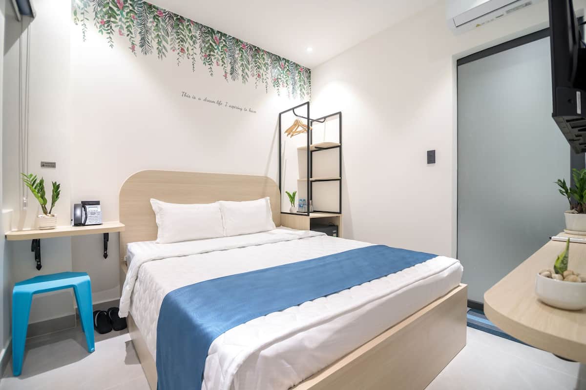 Une chambre à coucher moderne avec un lit, une table de chevet et un petit tabouret.
