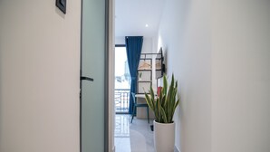 A hallway with a potted plant, a door, and a view of a balcony with a railing. - Bin Bin Hotel 16 - Near Bui Vien (Ho Chi Minh City)