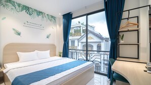 A hotel room with a bed, a desk, and a balcony with a view of a building. - Bin Bin Hotel 16 - Near Bui Vien (Ho Chi Minh City)