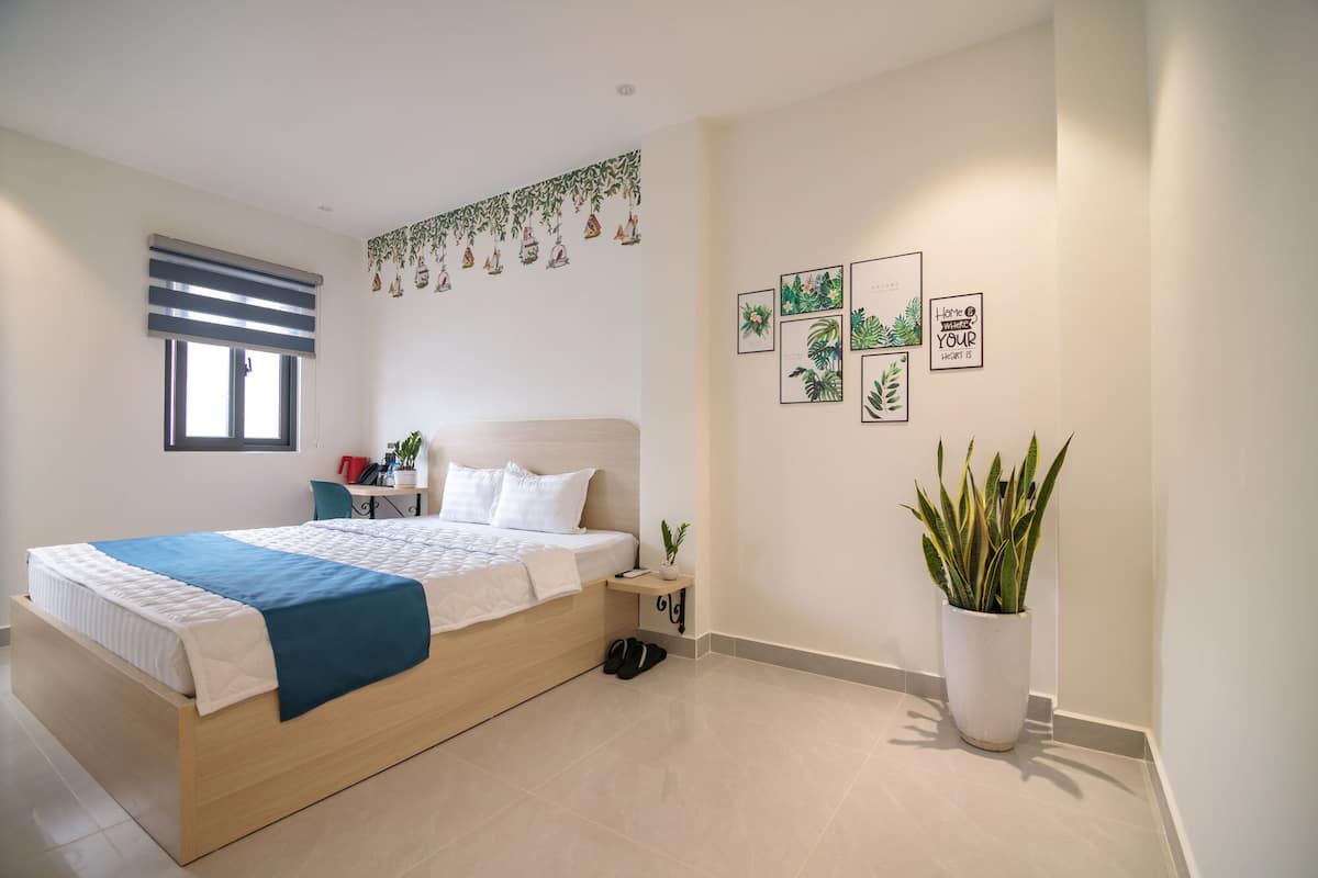 Une chambre à coucher avec un lit, une table de chevet, une plante en pot et des œuvres d’art murales.