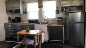 Eine kompakte Küche mit Kühlschrank, Spüle und einem kleinen Esstisch mit Stühlen.